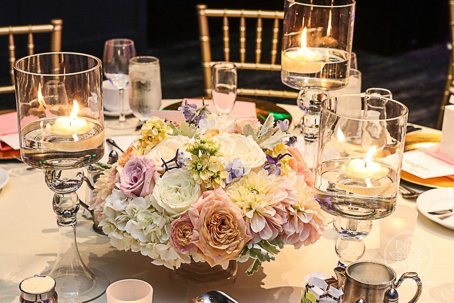 Elegant Hotel Wedding. Short reception centerpiece of hydrangea, roses, spray roses, dahlias, surrounded by floating candles.